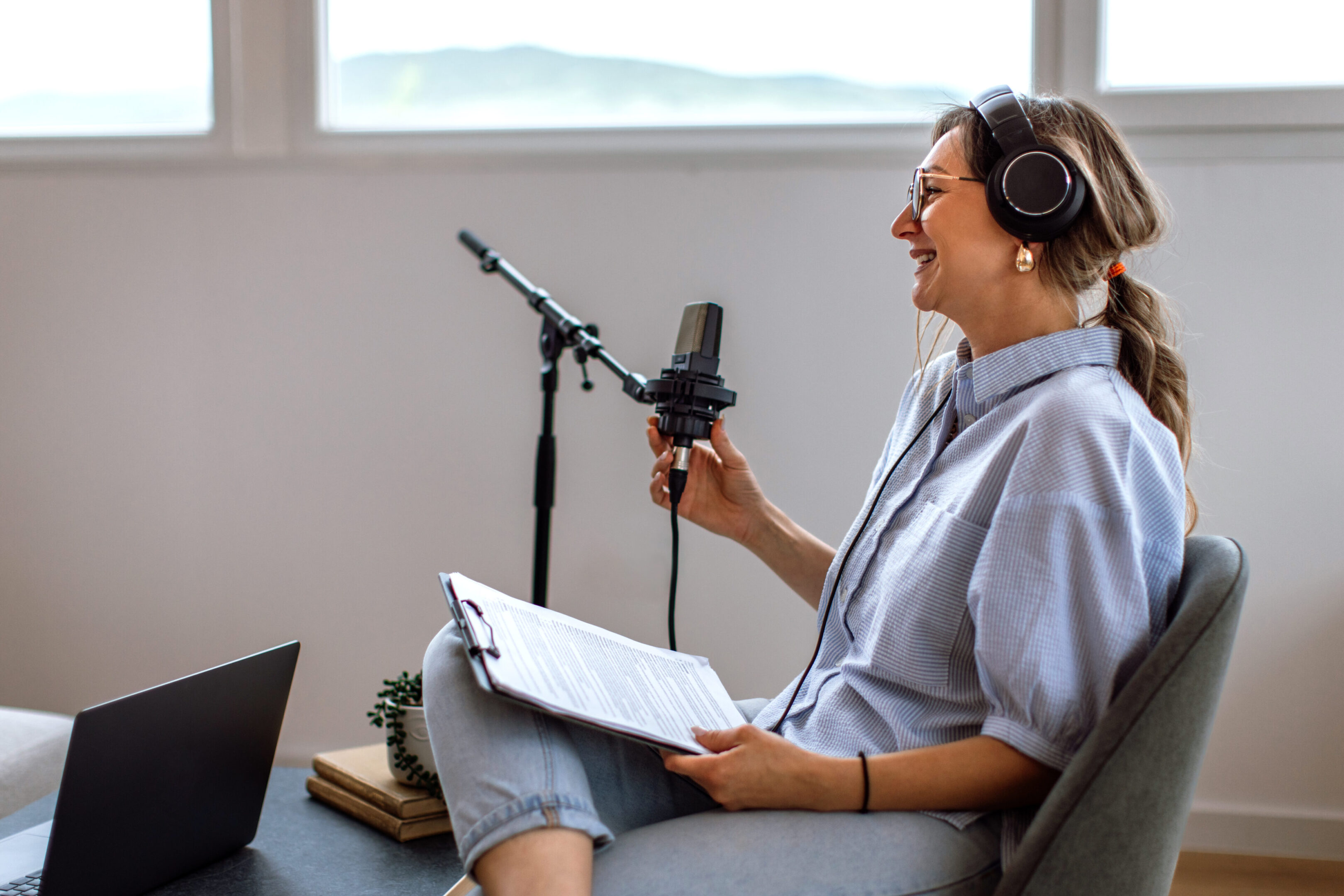 Woman recording podcast with microphone and headphones.