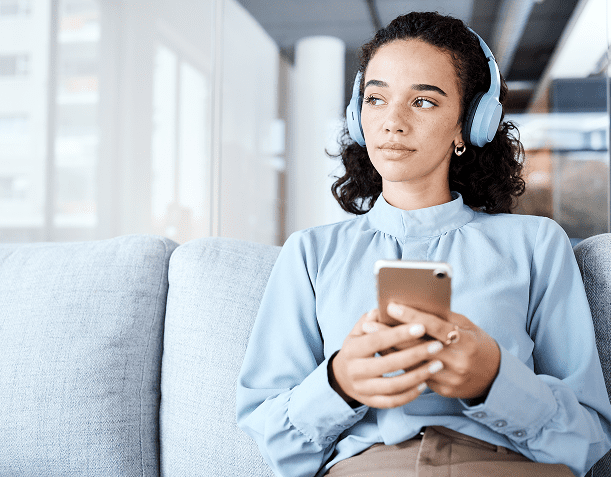 Relaxed woman holding phone wearing headphones