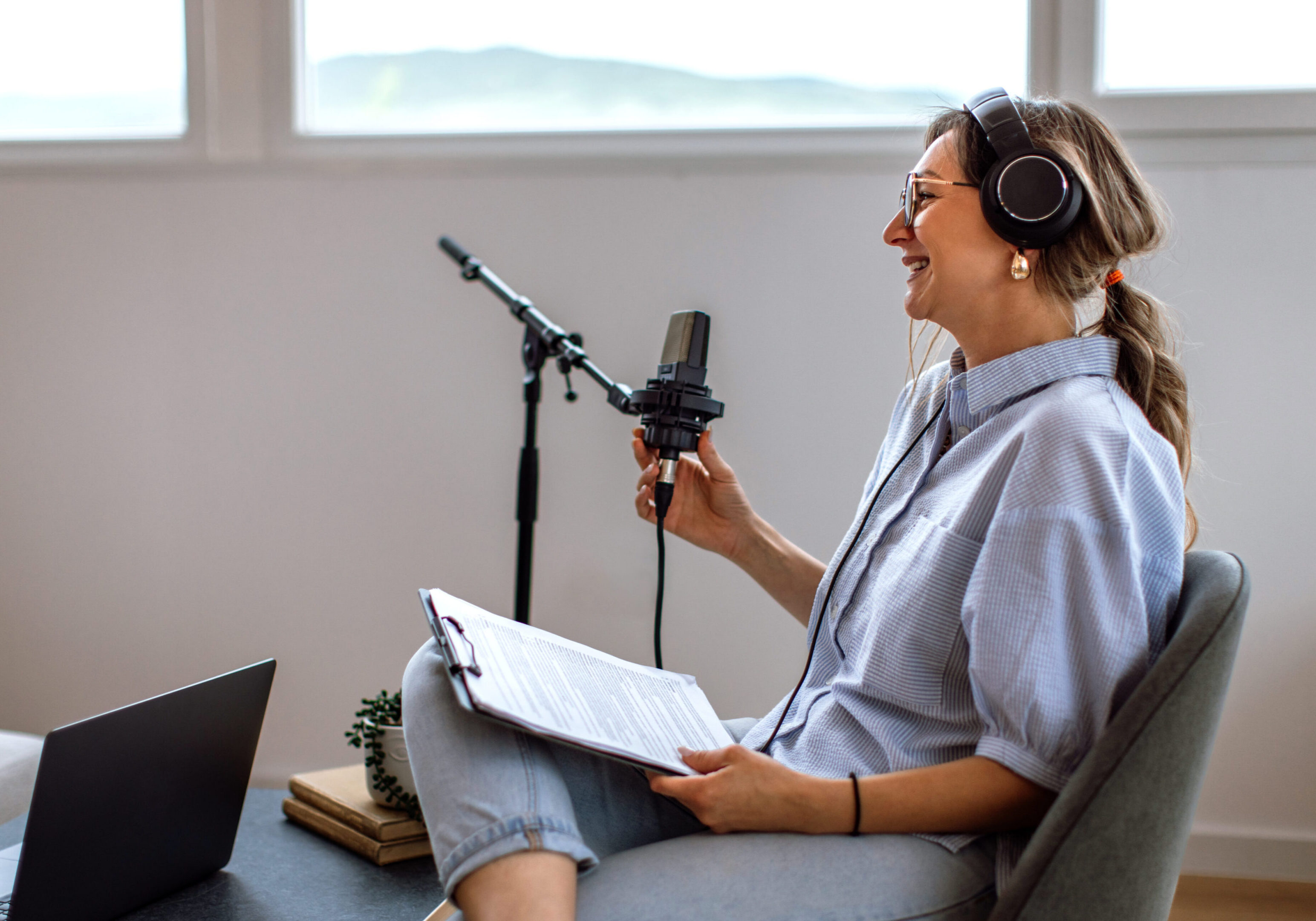 Woman recording podcast with microphone and headphones.